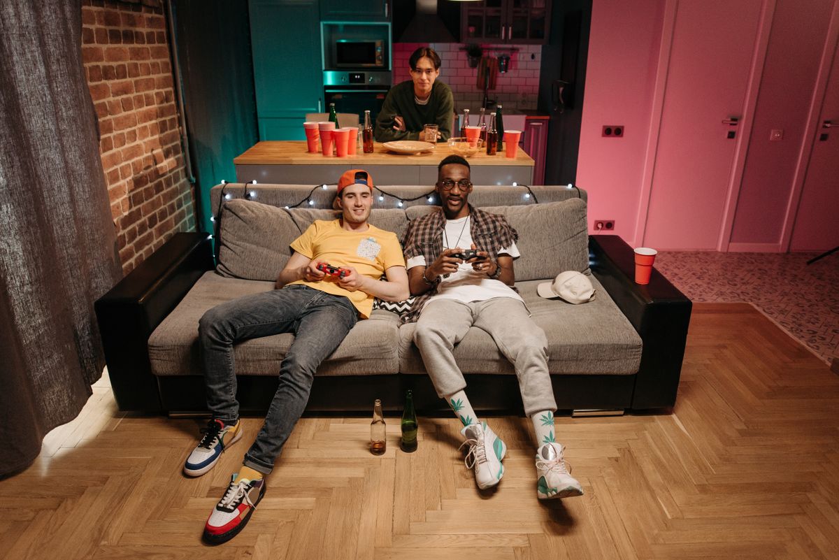 Three friends playing games together in a living room lit with coloured lights.