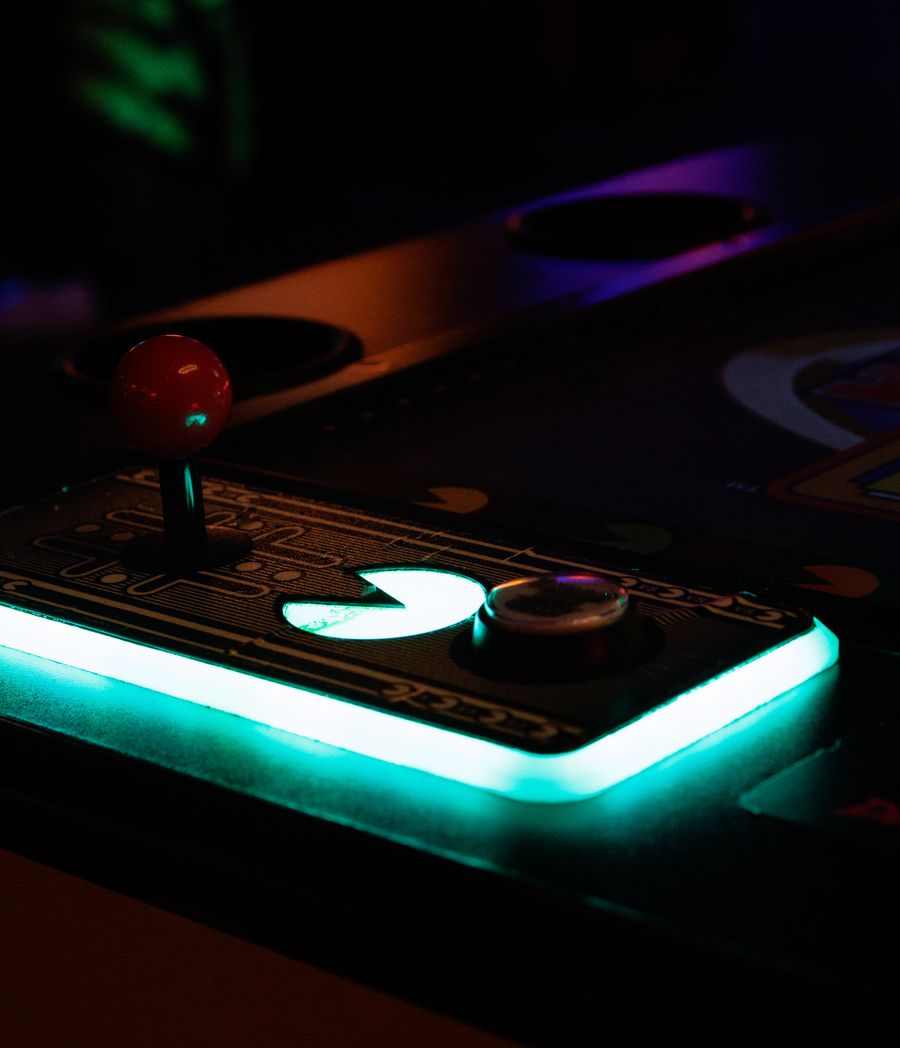 A glowing arcade joystick under violet ambient light.