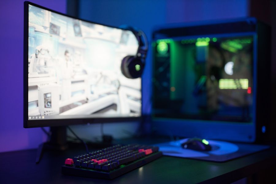 A desk setup with a curved monitor and RGB keyboard glowing in the dark.