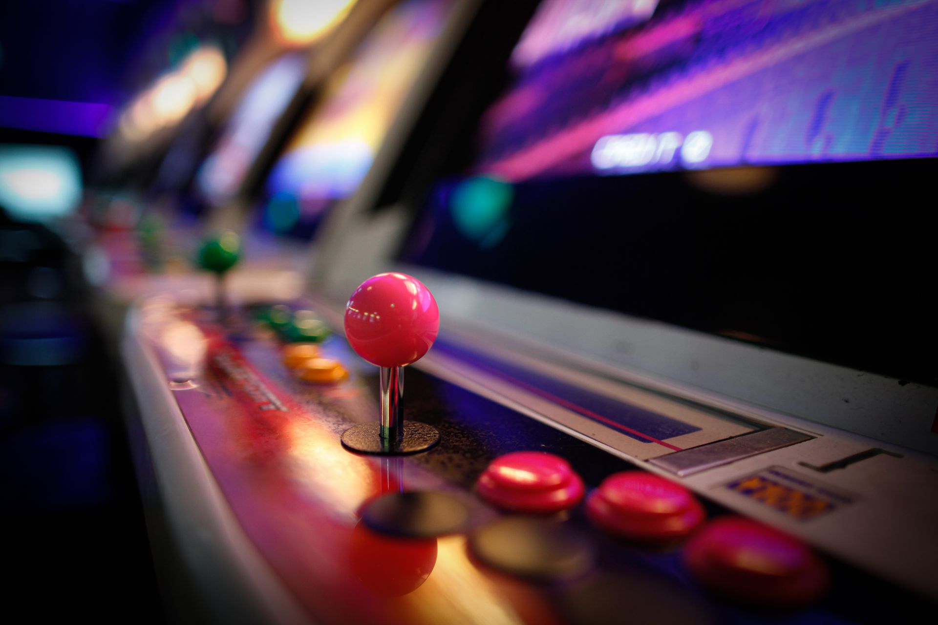 A vintage arcade cabinet glowing with violet and cyan light in a dim games room.